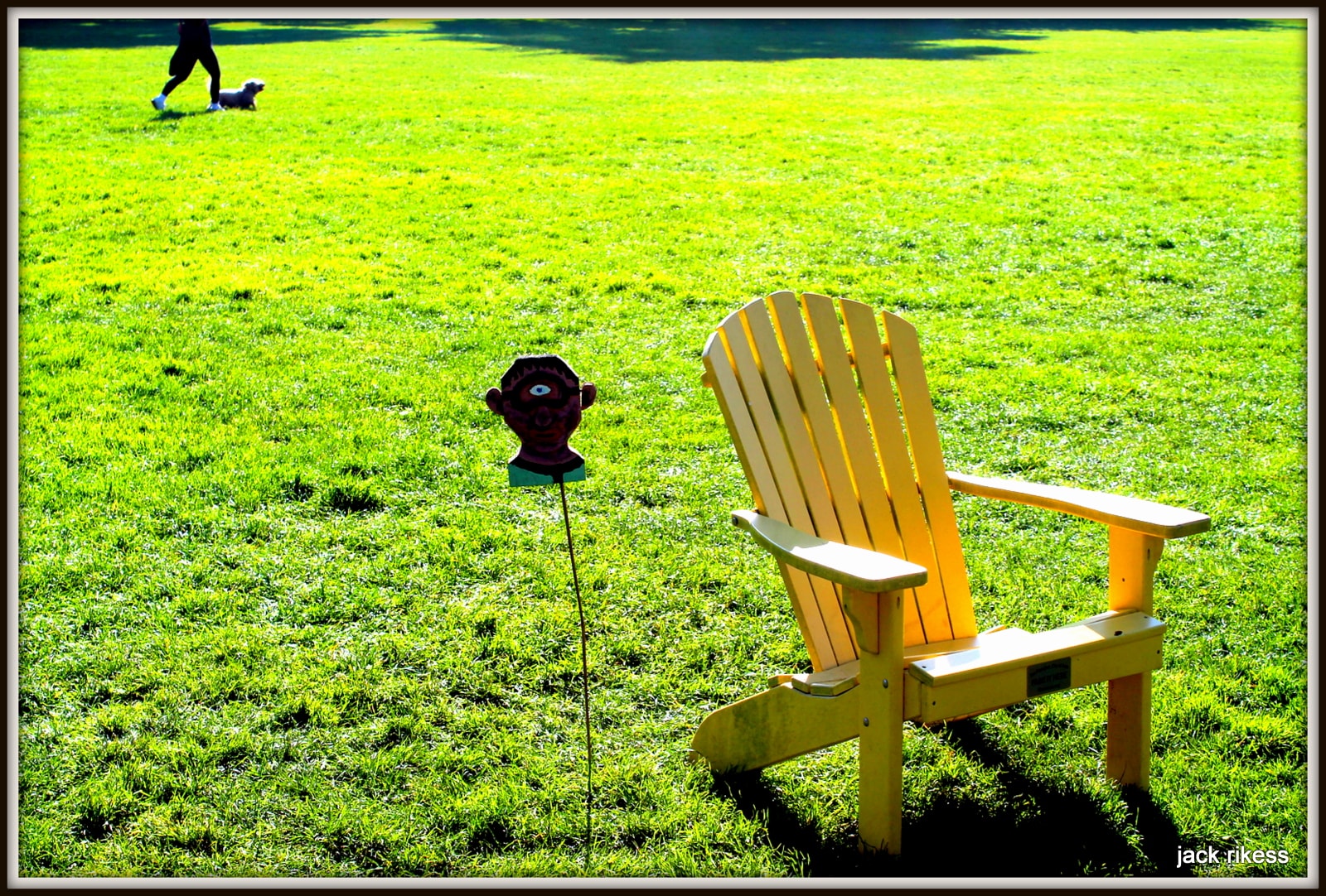 My Neighborhood — yellow Adirondack chair on green lawn with dog walker