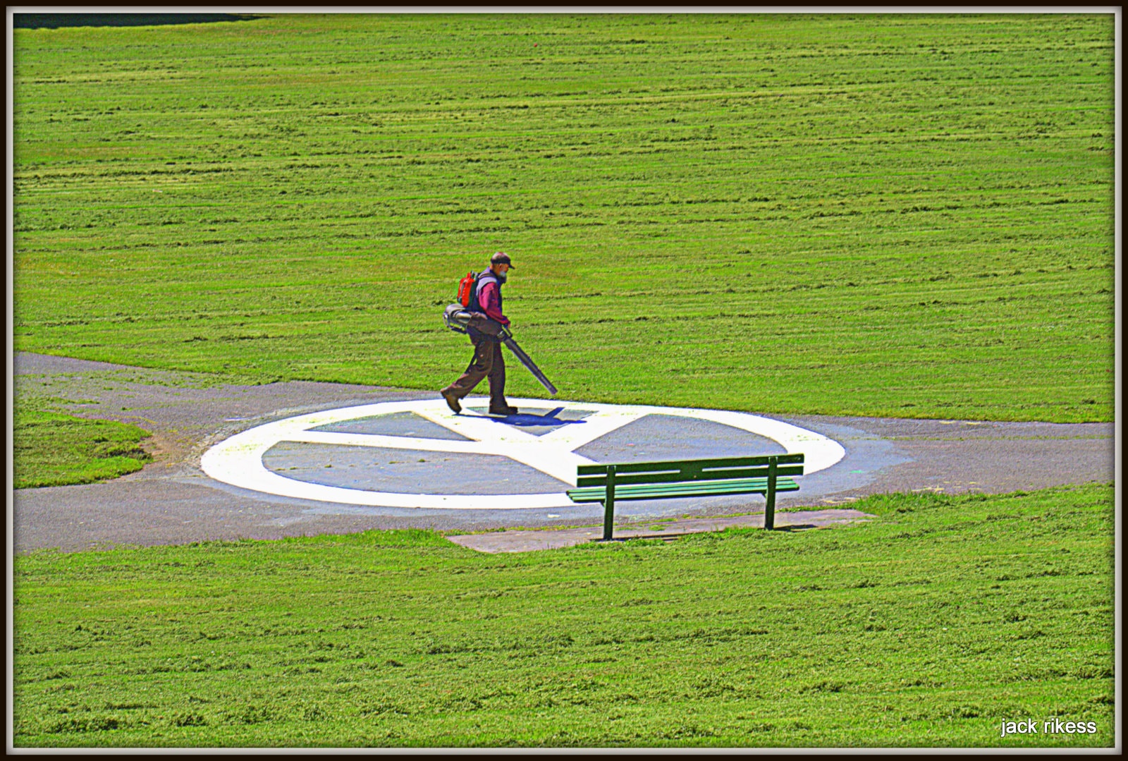 People — groundskeeper with leaf blower crossing a peace sign on the grass