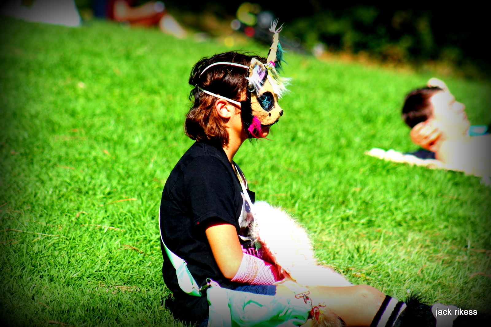 People — child in unicorn mask sitting on the grass