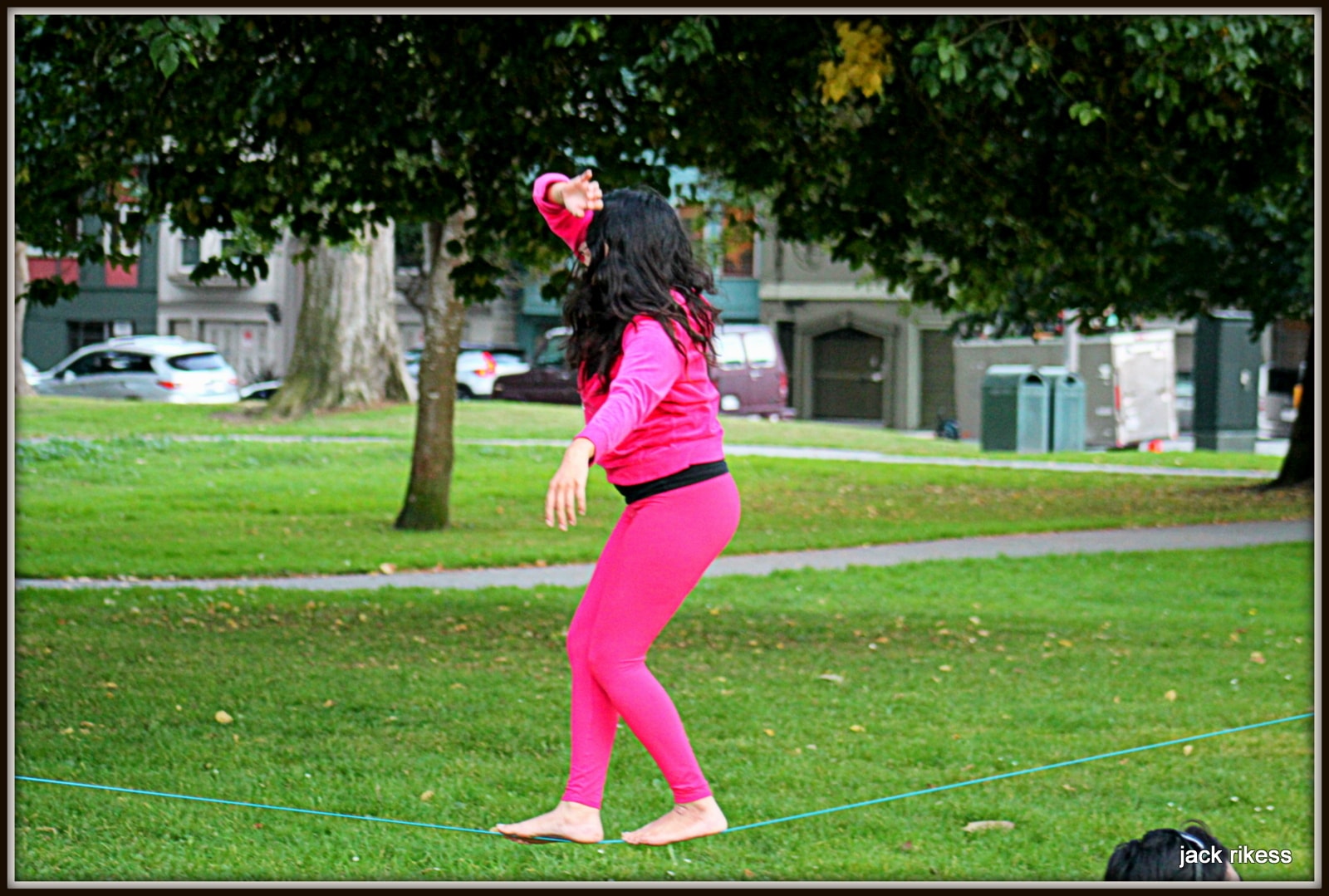 People — woman in pink walking a slackline in the park